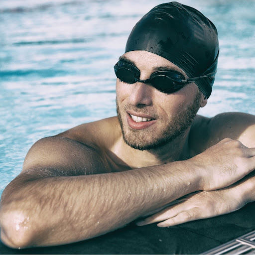 man wearing swim cap and goggles in pool